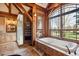 Serene bathroom featuring a soaking tub, stone accents, and expansive windows with outdoor views at 9250 Steeplechase Dr, Franktown, CO 80116