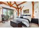Comfortable bedroom with exposed beams, a plush bed, and a large window offering scenic views at 9250 Steeplechase Dr, Franktown, CO 80116