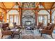 An inviting living room with a stone fireplace and rustic wood beams that create a cozy gathering space at 9250 Steeplechase Dr, Franktown, CO 80116