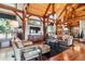 Cozy living room featuring exposed wood beams, plush seating, and a seamless flow to dining area at 9250 Steeplechase Dr, Franktown, CO 80116