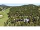 An aerial view shows the house surrounded by mature trees and vegetation, with rolling hills and mountain views at 2122 Cramner Ct, Evergreen, CO 80439