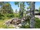 Backyard features a rock waterfall with lush greenery and mature trees creating a tranquil outdoor space at 2122 Cramner Ct, Evergreen, CO 80439