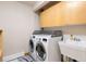 Bright laundry room with utility sink, overhead storage, modern washer and dryer, and clean tile flooring at 2122 Cramner Ct, Evergreen, CO 80439