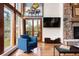 Living room features a stone fireplace, a painting of a piano, and views to the outside balcony at 2122 Cramner Ct, Evergreen, CO 80439
