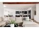 Open-concept living space with comfortable seating, wood beam ceilings, and seamless flow into the modern kitchen at 5985 Galena St, Denver, CO 80238