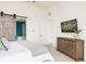 Bright main bedroom with a barn door to the en-suite bathroom and a dresser with a TV at 5985 Galena St, Denver, CO 80238