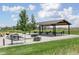 Outdoor picnic area with a covered shelter, picnic tables, and barbecue grills surrounded by green space at 5985 Galena St, Denver, CO 80238