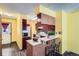 Compact kitchen with wood cabinetry, breakfast bar, and view into other rooms at 15566 E Louisiana Ave, Aurora, CO 80017
