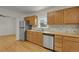 Spacious kitchen with stainless steel fridge, dishwasher, wooden cabinets and hardwood floors at 127 S Perry St, Denver, CO 80219