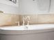 Close up shot of soaking tub with chrome hardware, white tile backsplash and natural light at 484 Hyland Dr, Castle Rock, CO 80108