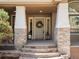 Inviting front porch with stone pillars, decorative lanterns, and wreath-adorned door at 484 Hyland Dr, Castle Rock, CO 80108