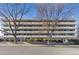 A multi-story apartment building with balconies and mature trees in front of a quiet street at 4600 E Asbury Cir # 202, Denver, CO 80222