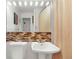 Cozy bathroom featuring a classic pedestal sink, neutral tile, and a well-lit mirror at 12020 W Center Ave, Lakewood, CO 80228