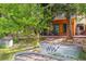 View of the backyard featuring raised garden beds, mature trees, and a modern, wood-sided home with large windows at 8966 Sunridge Hollow Rd, Parker, CO 80134