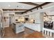 Spacious kitchen featuring a large island with seating, wood beams, white cabinets, and stainless steel appliances at 8966 Sunridge Hollow Rd, Parker, CO 80134