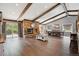 Open-concept living room with wood floors, exposed beams, stone fireplace, and dining area at 8966 Sunridge Hollow Rd, Parker, CO 80134