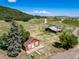 Aerial view of a property with a house, barn, and fields featuring a silo and hillside views at 4586 Best Rd, Larkspur, CO 80118