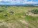 Expansive aerial view of a sprawling property featuring lush green fields, ponds, and a cluster of buildings at 4586 Best Rd, Larkspur, CO 80118