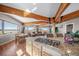 Open kitchen featuring a granite island with a stovetop, wood floors, and wooden beams at 4586 Best Rd, Larkspur, CO 80118