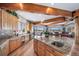 Open kitchen with wood cabinets, granite countertops, an island, wood floors, and wooden ceiling beams at 4586 Best Rd, Larkspur, CO 80118