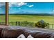 Stunning view of a mountain range from the home's living room window, enhanced by bright sunflowers and a cozy couch at 4586 Best Rd, Larkspur, CO 80118