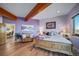Inviting bedroom with hardwood floors, wooden beams, purple walls, and outside views at 4586 Best Rd, Larkspur, CO 80118