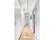 Hallway with hardwood floors, overhead lighting and multiple closets with a bathroom at the end at 1497 S Fairfax St, Denver, CO 80222