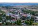 Expansive aerial view of a town nestled among green trees and rolling hills against a mountain backdrop at 4781 Rosette St, Castle Rock, CO 80104