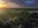 Scenic aerial view of a neighborhood with lush green trees, a body of water, and a beautiful sunset sky at 1424 Cypress Cir, Lafayette, CO 80026