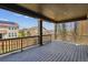 Large covered porch with wood flooring and railings, offering ample space for outdoor seating and overlooking the backyard at 13440 Monaco St, Thornton, CO 80602
