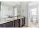Bright bathroom featuring double sinks, dark cabinets, and a separate toilet and shower area for added convenience at 13440 Monaco St, Thornton, CO 80602