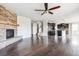 Open-concept living space with a stone fireplace, hardwood floors, and adjacent kitchen at 13440 Monaco St, Thornton, CO 80602