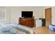 Interior view of the bedroom featuring a dark wood dresser, TV, and laminate floors at 17034 E Tennessee Dr # 105, Aurora, CO 80017