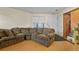 Cozy living room area showcasing a sectional sofa, laminate floors, and a sunlit window with white blinds at 17034 E Tennessee Dr # 105, Aurora, CO 80017