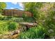Backyard featuring a small bridge over a stream, surrounded by lush greenery and a wooden fence at 4425 Irving St, Denver, CO 80211