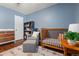 Light filled bedroom features hardwood floors, a crib, a glider, a changing table and a bookcase at 4425 Irving St, Denver, CO 80211