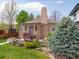 Inviting exterior showcasing a brick home, chimney, manicured lawn, and a charming front porch with a pergola at 4425 Irving St, Denver, CO 80211