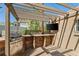 Outdoor kitchen area featuring a built-in grill, bar, and a covered pergola with a wall-mounted television at 4425 Irving St, Denver, CO 80211