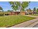 Charming single-story brick home with a well-manicured lawn and mature tree in front at 13624 Omega Cir, Lone Tree, CO 80124