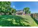 Spacious backyard features lush green grass, a wood fence, mature trees, and a covered patio ideal for relaxing outdoors at 7118 W Elmhurst Ave, Littleton, CO 80128