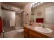 Well-lit bathroom featuring a vanity with sink, framed mirror, and a shower-tub combination with glass doors at 2151 Burbank St, Berthoud, CO 80513