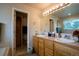 Bathroom featuring double sinks, wood cabinets, and access to an adjacent room at 2151 Burbank St, Berthoud, CO 80513