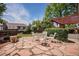 Outdoor patio with stone pavers, white furniture, pergola, trimmed bushes, and mature trees at 7655 S Ogden Way, Centennial, CO 80122