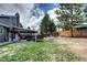 Spacious backyard with lush lawn, tiered garden beds, mature trees, and covered patio at 8581 W Hinsdale Pl, Littleton, CO 80128
