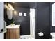 Stylish bathroom featuring black walls, wooden vanity, updated fixtures, and walk-in shower at 8581 W Hinsdale Pl, Littleton, CO 80128