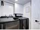 Functional laundry room with modern washer and dryer, white cabinets, and a storage shelf at 8581 W Hinsdale Pl, Littleton, CO 80128