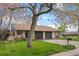 Charming brick home with a well-manicured lawn, mature trees, and a cozy front porch at 1002 Zang St, Golden, CO 80401