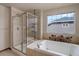 Main bathroom features a glass enclosed shower and tub with tile surround and floral accents at 1348 Lawson Ave, Erie, CO 80516