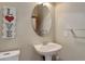 Modest powder room featuring an oval mirror, single sink vanity, and modern light fixtures at 1348 Lawson Ave, Erie, CO 80516