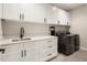 Well-lit laundry room with modern appliances and white cabinets and sleek black hardware at 3427 S Cherry St, Denver, CO 80222